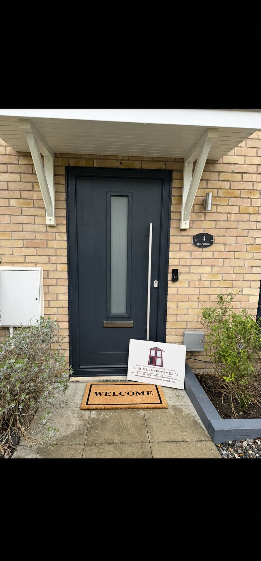 Anthracite grey composite front door with a frosted glass panel beneath a timber porch canopy