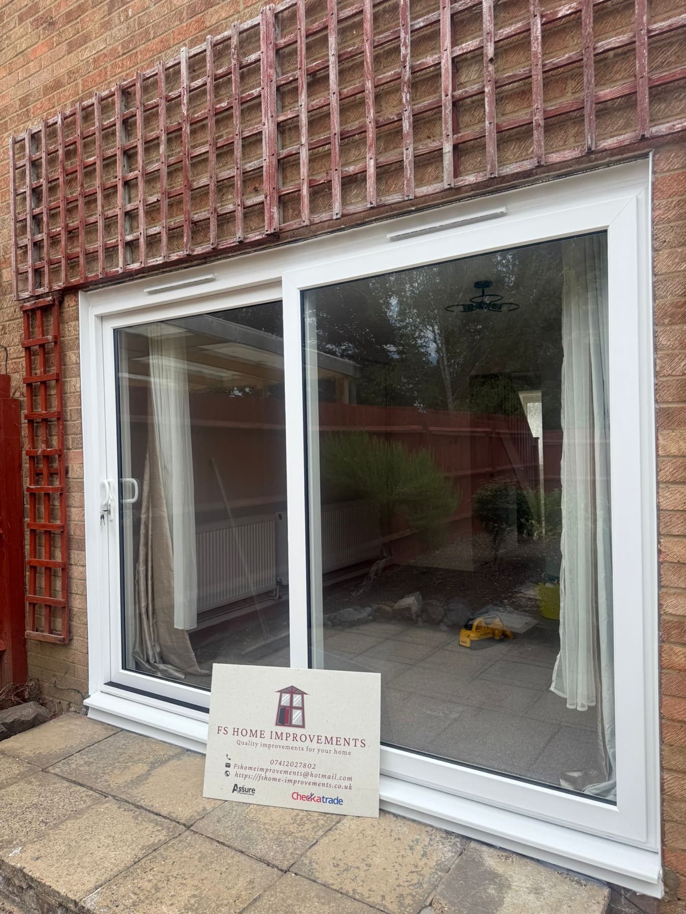 Two-panel white uPVC sliding patio doors fitted to a brick rear elevation, opening onto a paved garden patio
