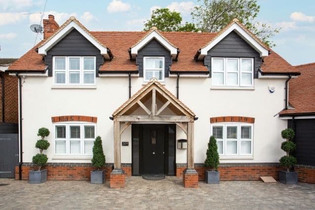 Detached home with an oak-framed porch, black front door and white shuttered windows