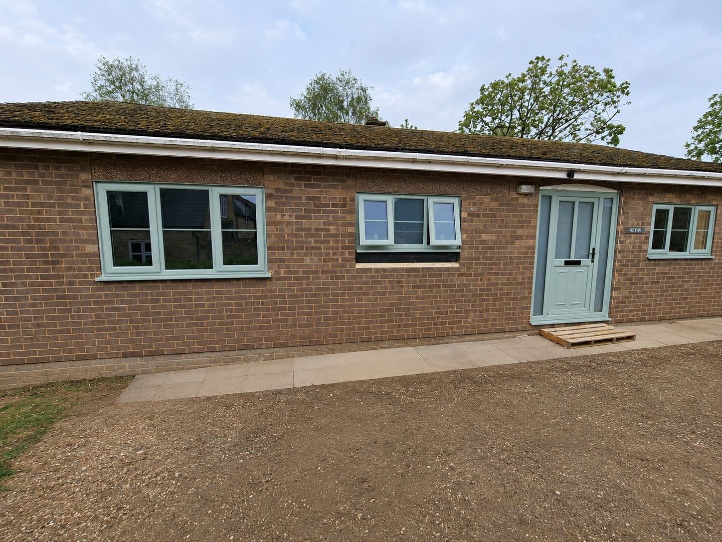 Sage green uPVC windows and matching composite front door fitted to a brick bungalow