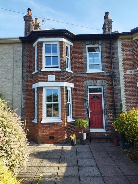 White uPVC sash windows on a Victorian terrace beside a red front door